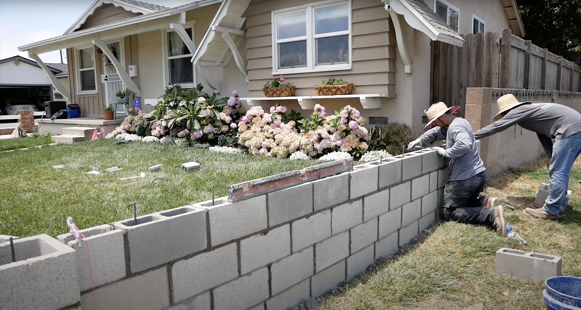 Professional residential concrete block wall and retaining wall construction Residential concrete block wall construction with workers building retaining wall