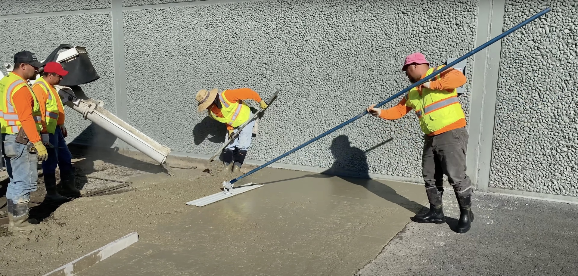 Professional concrete installation team using screeding techniques for large commercial concrete projects Professional concrete crew using screeding tools to level large commercial concrete pour